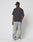 A person in a black cap, LIVE FAST DIE YOUNG LFDY Monaco Boys Tee in dark gray Oversize Fit, baggy light-wash jeans in Vintage Optik, and white sneakers stands against a plain white background with hands in pockets, looking to the side.