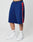 A person wears oversized blue LIVE FAST DIE YOUNG Striped Mesh Shorts with red and white side panels, elastic waistband, vertical FACT print, white LFDY socks, white sneakers, and has a visible tattoo on the lower right leg.
