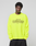 Wearing the LFDY Real Est.8 Longsleeve by LIVE FAST DIE YOUNG, an oversize neon yellow 100% Baumwolle shirt with black "Approval GUARANTEED Credit Score Irrelevant" prints, a person stands against a plain light gray background.