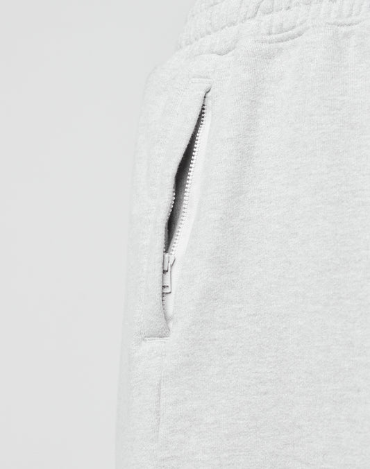 Close-up of a Ripped College Shorts pocket by LIVE FAST DIE YOUNG, featuring light gray fabric, a white zipper, and part of the elastic waistband. The shorts have an oversize fit and are set against a plain, light background.