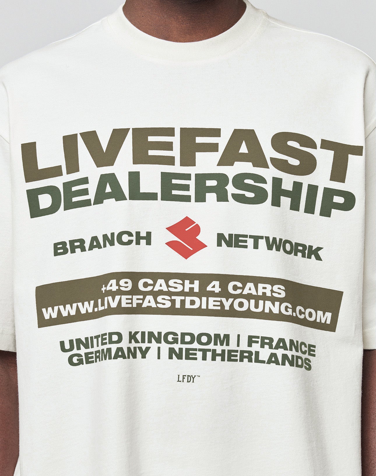 Wearing the LFDY Network Tee by LIVE FAST DIE YOUNG, a white 100% cotton oversize fit shirt with a bold front print: LIVEFAST DEALERSHIP, BRANCH NETWORK, +49 CASH 4 CARS, www.livefastdieyoung.com, and UK, France, Germany, Netherlands.