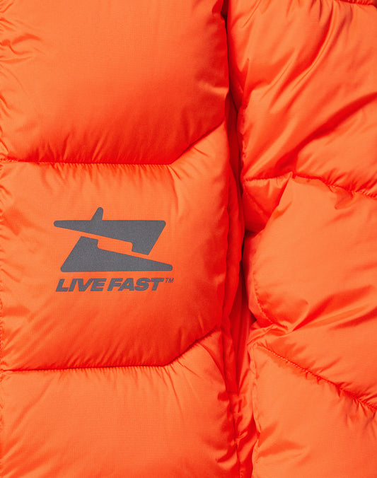 Close-up of the Live Fast Puffer Jacket by LIVE FAST DIE YOUNG: an oversized bright orange jacket with quilted texture, visible stitching, navy blue LIVE FAST logo graphic, and reflective print.