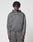 A person with medium-length curly hair wears the LFDY Active Fleece Hooded Zip by LIVE FAST DIE YOUNG in grey Oversize Fit, paired with matching pants, standing against a plain light background and looking directly at the camera with a neutral expression.