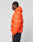 A person in profile wears the Live Fast Puffer Jacket by LIVE FAST DIE YOUNG—an orange, water-repellent hooded jacket—paired with dark jeans, standing against a plain, light gray background.