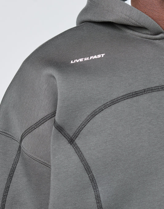 Close-up of the LFDY Active Fleece Hooded Zip by LIVE FAST DIE YOUNG, an oversize fit charcoal gray hoodie in cotton, featuring black seam detailing and a small white LIVE FAST logo print on the chest.
