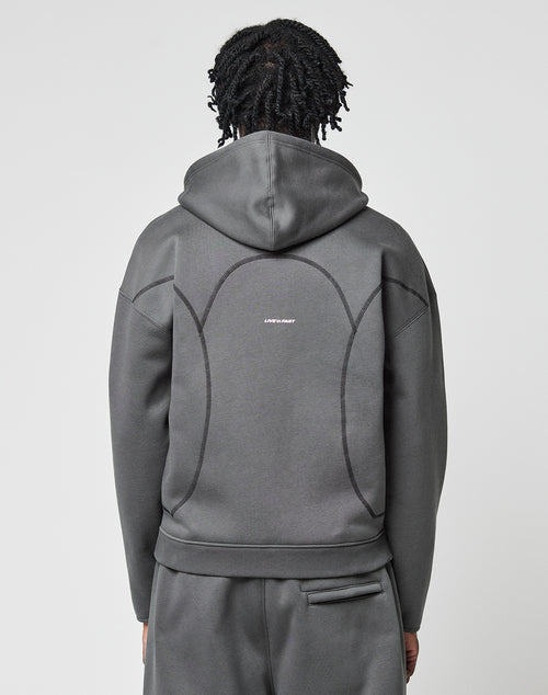 A person with short, twisted hair is seen from the back wearing the LIVE FAST DIE YOUNG LFDY Active Fleece Hooded Zip—a gray, oversized sweatshirt in 100% Baumwolle, with curved seams and a small white Live Fast logo on the upper back.