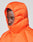 A person wears the LIVE FAST DIE YOUNG Live Fast Puffer Jacket in bright orange, featuring an oversized fit and hood zipped up to cover most of their head. The background is plain light gray.