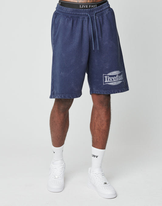 A person wearing LIVE FAST DIE YOUNG LFDY Bulge Shorts, white socks, and white sneakers stands against a plain white background.