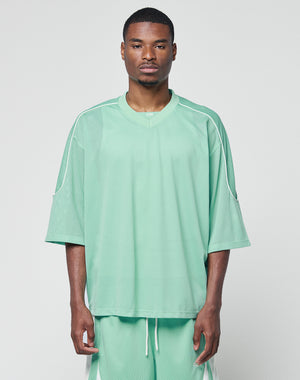 A man wearing the LIVE FAST DIE YOUNG Basic Mesh Jersey and matching mint green shorts with contrast piping stands against a white background, looking directly at the camera with a neutral expression.