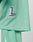 A close-up of the mint green Basic Mesh Jersey by LIVE FAST DIE YOUNG, featuring 100% polyester mesh and a patch with a large L and LIVEFAST. Matching shorts with a white stripe and contrast piping are partially visible.