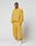 A man stands against a white background, hands in pockets, wearing LIVE FAST DIE YOUNG LFDY Trackpants—loose-fitting mustard yellow polyester with Elastikbund and reflective print—confidently looking at the camera.