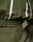 Close-up of an olive green LFDY Nylon Trackjacket by LIVE FAST DIE YOUNG, featuring crinkled fabric, white reflective stripes, Velcro strap, elastic hood drawstring, embossed patch detail, and an oversize fit for comfort.