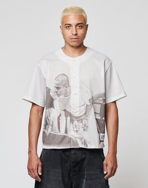 A person with short, bleached blond hair wears the LIVE FAST DIE YOUNG LFDY Courtroom Jersey, an oversized light short-sleeve shirt with a large grayscale print of two people, standing facing the camera against a plain background.