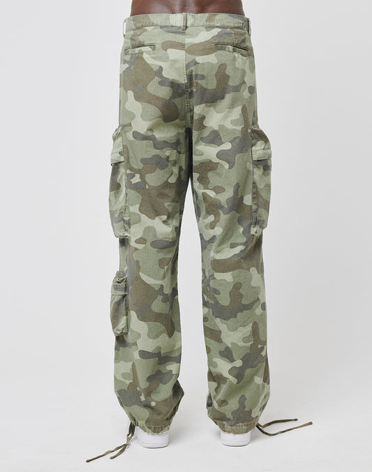 A person is seen from the back wearing LIVE FAST DIE YOUNG Army Cargo pants—wide fit, green camouflage, with Cargo Taschen and ankle drawstrings in durable Ripstop Stoff—against a plain white background.