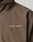 Close-up of the LFDY Trackjacket by LIVE FAST DIE YOUNG, a brown oversized polyester jacket with LIVE FAST in white capitals, a small stylized runner, and reflective print on the left chest.