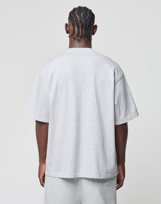 A person with braid-style cornrow hair stands with their back to the camera, wearing the LIVE FAST DIE YOUNG Basic Tee and matching shorts in light gray Baumwolle-Polyester blend, featuring an oversize fit against a plain light background.