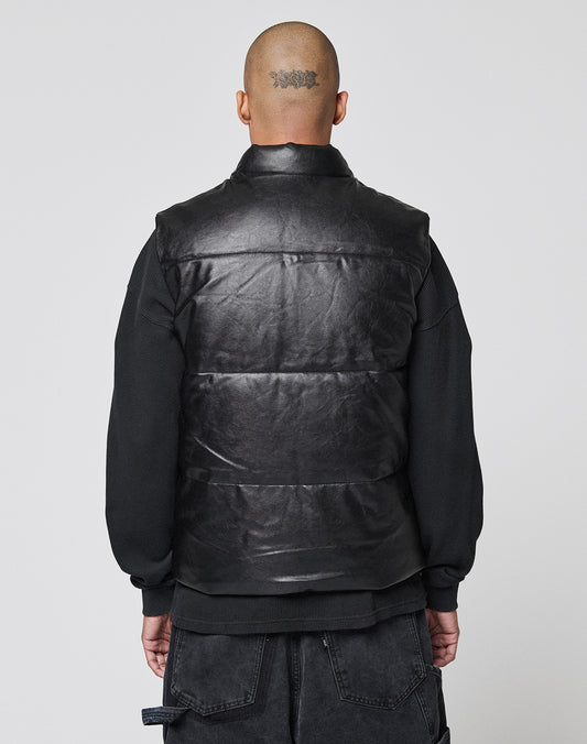 A person with a shaved head and a head tattoo is seen from behind, wearing the LIVE FAST DIE YOUNG Padded Vest in black over a black sweatshirt, standing against a plain light background.