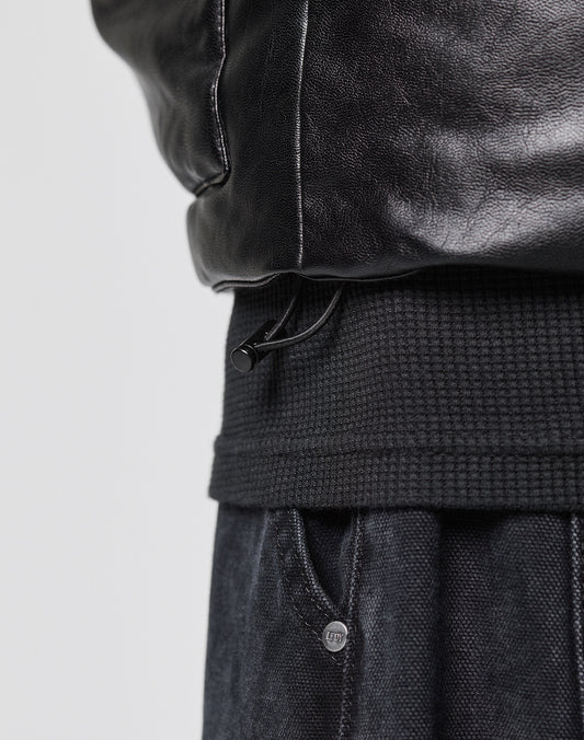 Close-up of the lower section of the LIVE FAST DIE YOUNG Padded Vest featuring a ribbed waistband, visible adjustable drawstring, gepaddeter Stehkragen, and a glimpse of dark textured pants underneath.