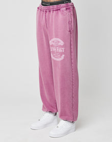 A person wears the Loyal Loose Jogger by LIVE FAST DIE YOUNG—oversized pink sweatpants with a white LIVE FAST print on one leg, made of soft Baumwolle—paired with white sneakers. Only their lower half is visible against a plain background. | model