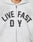 A person wears the Live Fast Rivet Hooded Zip by LIVE FAST DIE YOUNG—a light gray, oversized zip-up hoodie featuring bold black and white LIVE FAST D Y lettering across the chest. Only their lower face and upper torso are shown.
