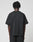 A person with short, twisted hair is seen from behind, wearing the oversize fit LIVE FAST DIE YOUNG Basic +49 Tee, made of 100% Baumwolle, and black pants against a plain white background.