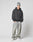 A person in a gray beanie, LIVE FAST DIE YOUNG LFDY Core Hooded black hoodie with Logo-Stick, light baggy Oversize Fit jeans aus Baumwolle, and white sneakers stands hands-in-pockets against a plain light background.