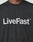 A person wears the Basic LiveFast Tee by LIVE FAST DIE YOUNG, a black regular-fit cotton T-shirt with a bold LiveFast™ front print in large white letters across the chest.