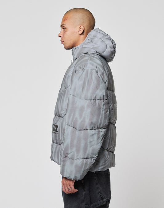 A person with a shaved head stands in profile against a white background, wearing black pants and the Live Fast Puffer Jacket by LIVE FAST DIE YOUNG.