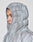 A person wearing the LIVE FAST DIE YOUNG Live Fast Puffer Jacket in shiny silver with the hood up, fully zipped, looks left. The thick, water-repellent jacket covers most of their head except for the face.