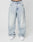 A person wears LFDY Baggy Denim by LIVE FAST DIE YOUNG—loose, light-wash blue jeans with a wide straight leg in 100% cotton. Only the lower torso and legs are shown, paired with white sneakers against a plain white background.