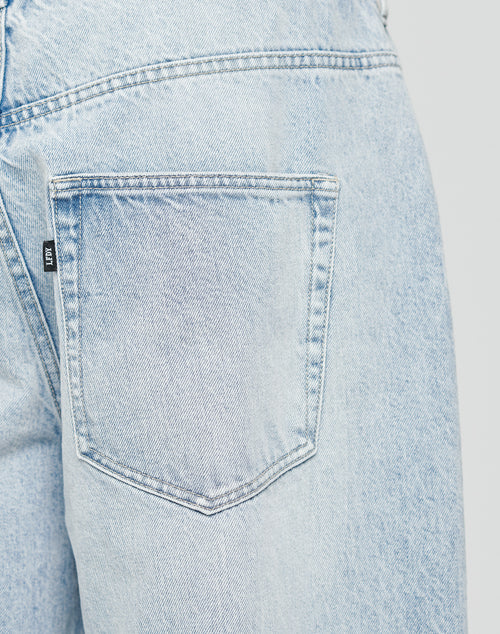 Close-up of the back pocket and waistband of LFDY Baggy Denim by LIVE FAST DIE YOUNG in light blue, crafted from 100% Baumwolle, with detailed stitching and a small black label on the pockets side.