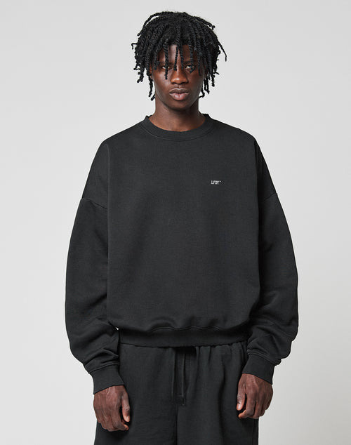 A man wearing the LIVE FAST DIE YOUNG Basic Evidence Sweater, an oversized black cotton-polyester sweatshirt with stylish front and back prints.
