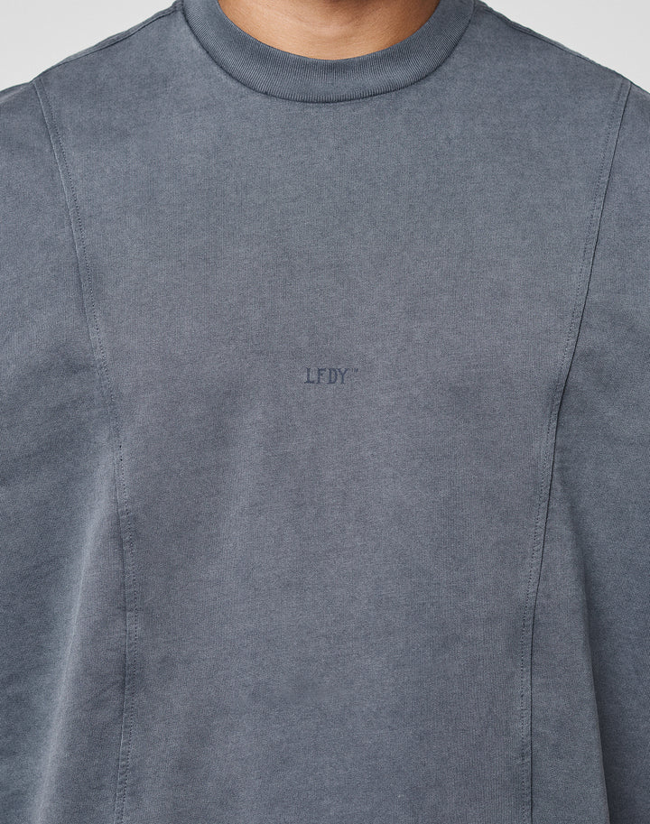 A person wears the Heavy Muscle Tank by LIVE FAST DIE YOUNG, featuring an oversized fit in faded grey with a small LFDY frontprint. Only the upper torso and neck are shown, without any visible background.