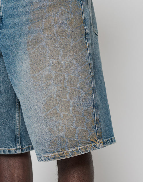A close-up of a person wearing LFDY Tire Tracks Jorts from LIVE FAST DIE YOUNG—light blue, 100% Baumwolldenim shorts with a unique bleach pattern, visible seams, and a baggy fit for comfort and style.