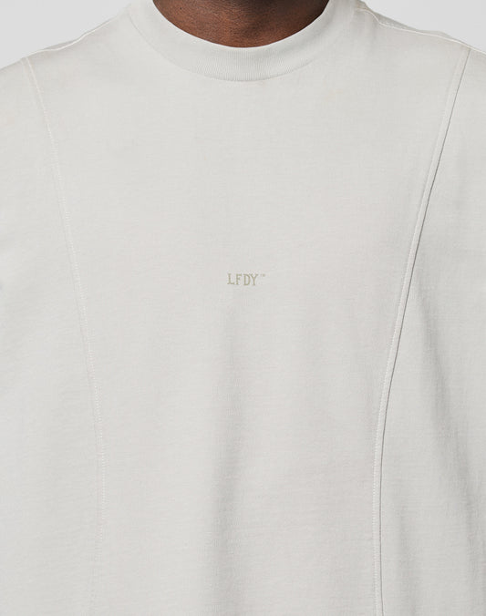 A close-up of a person wearing the LIVE FAST DIE YOUNG Heavy Muscle Tank in light grey, made from soft Baumwolle with subtle panel stitching and a small LFDY frontprint centered on the chest.