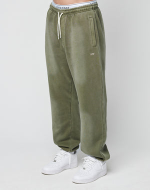 A person wearing olive green Basic Loose Jogger sweatpants by LIVE FAST DIE YOUNG with side pockets, white sneakers, and an elastic waistband with white drawstrings. The visible underwear features a bold “LIVE FAST” logo print.