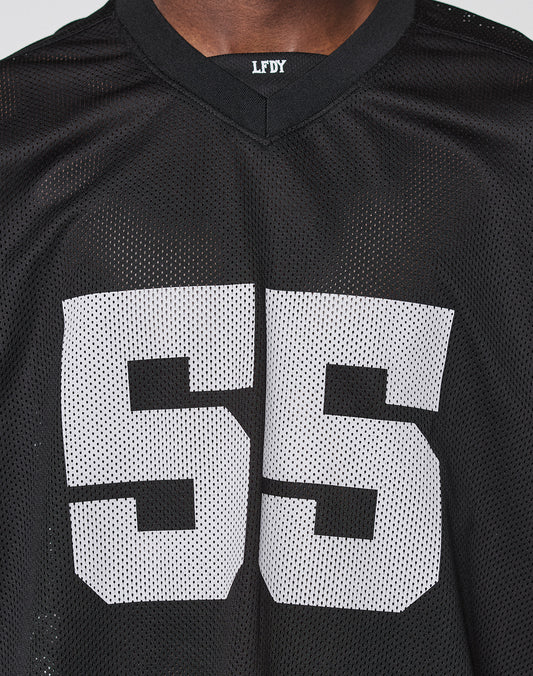 Close-up of a person in the LFDY Mesh Jersey by LIVE FAST DIE YOUNG—an oversized black polyester sports jersey with a subtle V-Ausschnitt, large white “55” on the front, and small LFDY text on the neckline.