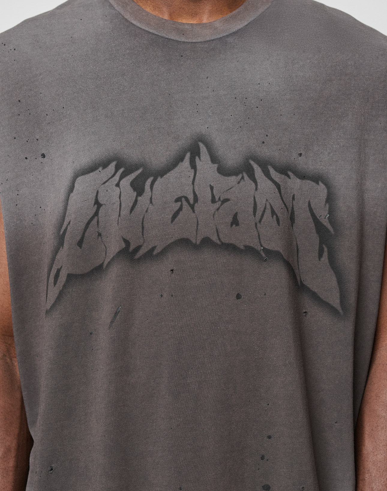 A person wearing an oversize, faded black LFDY Flames Muscle Shirt by LIVE FAST DIE YOUNG with "LIVECAVT" in bold graffiti print and hand-applied spray effect on 100% cotton.
