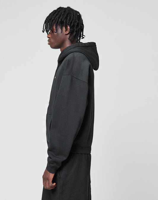 A person with short, twisted hair wears a black LIVE FAST DIE YOUNG Basic Hooded Zip and black pants, standing sideways against a plain light gray background.