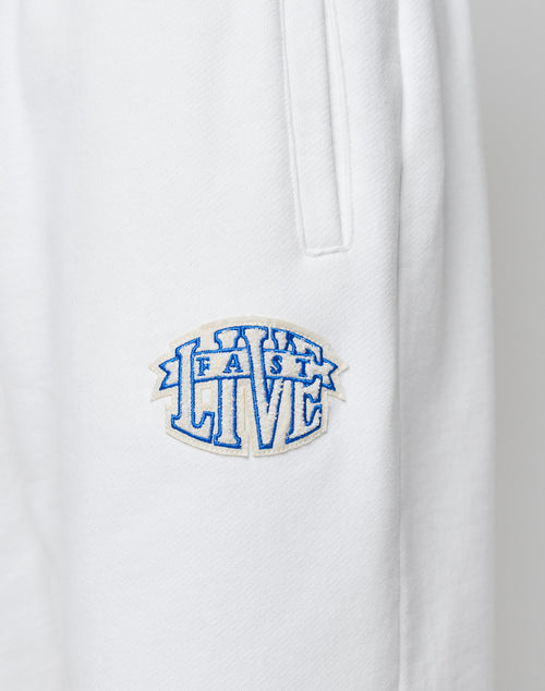 Close-up of LFDY Radiator Sweatpants in white from LIVE FAST DIE YOUNG, featuring an elastic waistband and a blue and white chenille LIVE FAST patch below the side pocket.