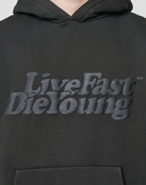 Close-up of the Basic Hooded by LIVE FAST DIE YOUNG: a black oversized hoodie with Live Fast Die Young in bold, raised letters on the chest, crafted from a soft cotton-polyester blend for comfort and durability.