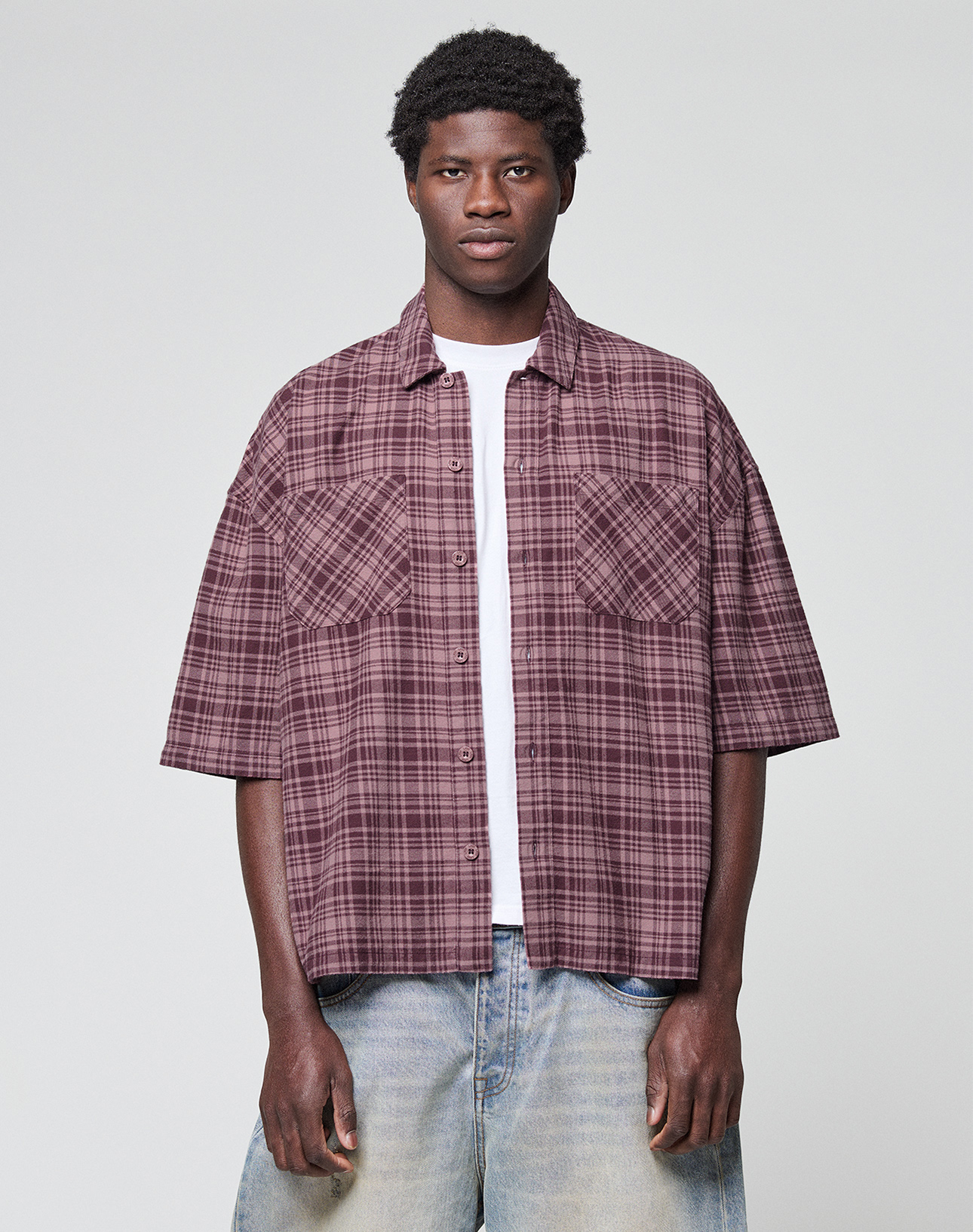 A person stands against a plain light background wearing the LFDY Light Flannel in maroon plaid by LIVE FAST DIE YOUNG, layered over a white t-shirt and light blue jeans, looking directly at the camera with a neutral expression.