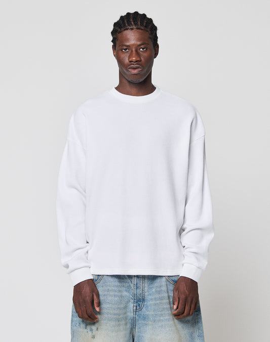 A man with braided hair wears the LIVE FAST DIE YOUNG NY-FW Waffle Longsleeve and faded blue jeans, standing facing forward against a light gray background.