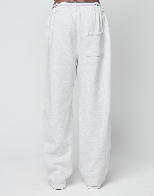 A person wears LIVE FAST DIE YOUNG Basic Wide Jogger sweatpants in light gray, featuring an oversized fit, elastic waistband with drawstring, and a single back pocket, standing against a plain white background.