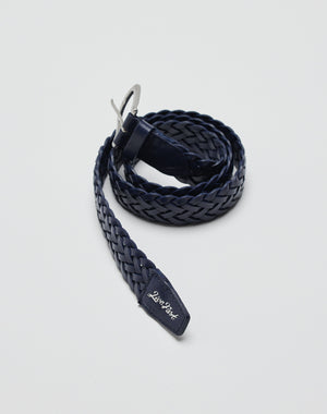 A coiled, navy blue LFDY Braided Belt made of 100% cow leather with a silver buckle and a small tag at the tip showing the LIVE FAST DIE YOUNG brand name in white, set against a plain white background.