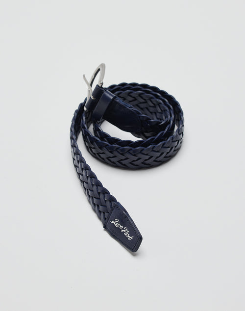 A coiled, navy blue LFDY Braided Belt made of 100% cow leather with a silver buckle and a small tag at the tip showing the LIVE FAST DIE YOUNG brand name in white, set against a plain white background.