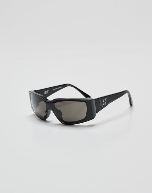 LIVE FAST DIE YOUNGs Live Fast Curved Shades are black rectangular sunglasses with dark lenses, made from Mazzuchelli Acetate, offering 400 UV protection and LIVE FAST in white on the left temple, shown on a plain white background.