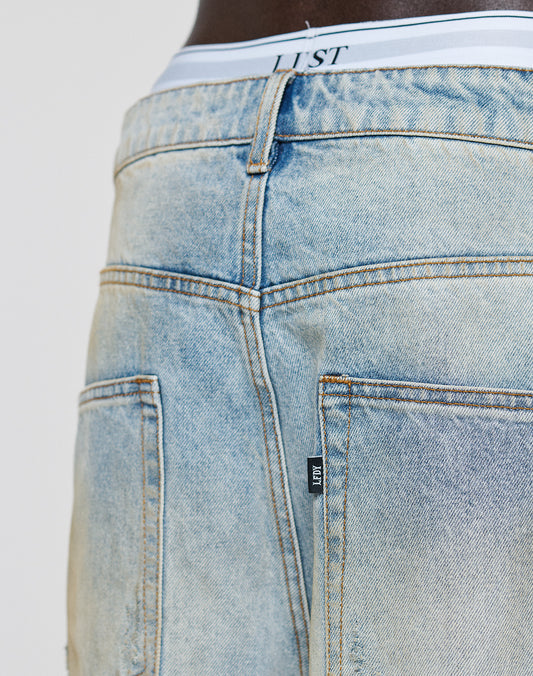 Close-up of the back of LFDY Baggy Dirt Denim by LIVE FAST DIE YOUNG, featuring visible stitching, two pockets, and a baggy fit with gerades Bein. A white elastic waistband labeled LUST peeks above these 100% Baumwolle jeans.