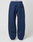 A person in LIVE FAST DIE YOUNG's LFDY Active Fleece Jogger—wide fit navy sweatpants with black seams and a flap pocket—paired with white shoes, stands against a plain light background.