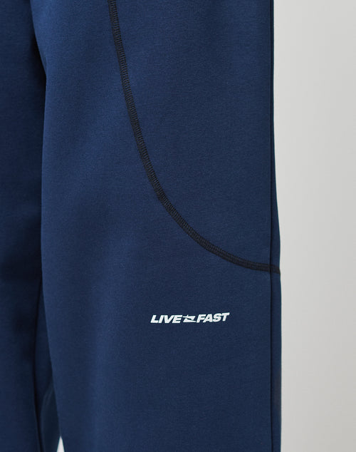 Close-up of LFDY Active Fleece Jogger by LIVE FAST DIE YOUNG, blue athletic Wide Fit hose with black seam detailing, zip pockets, and a bold white LIVE FAST logo near the pocket.